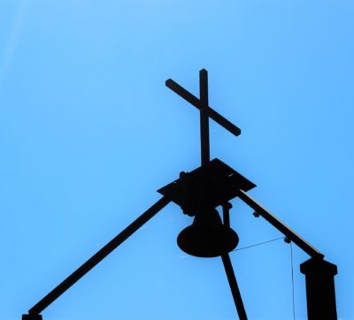 Cross and bell against blue sky